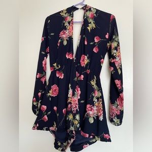 Navy blue romper featuring an allover floral print, v-neckline front and back.